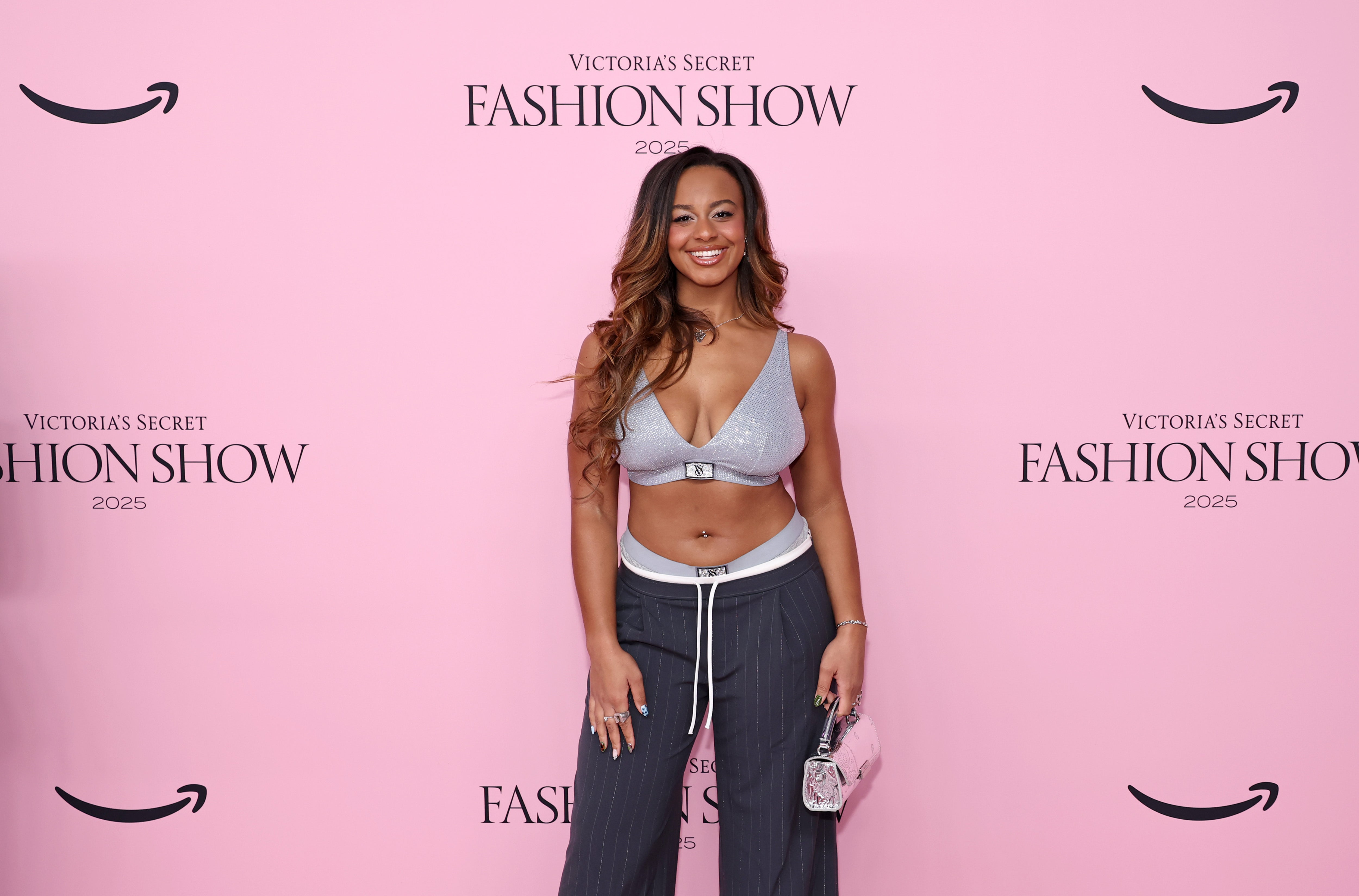Dance Moms alum Nia Sioux opted for a silver sparkly Victoria's Secret bra, pinstripe pants that appear to be a sweatpant-trouser hybrid, and glittery open-toed shoes. Her look seems to be a nod to the fact that Victoria's Secret, known for its lingerie, has ventured further into apparel and athleisure